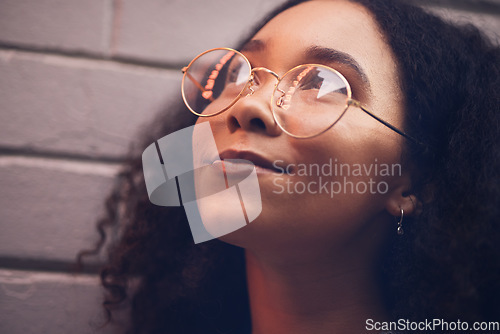 Image of .Face, thinking and glasses with a black woman in the city at night against a brick wall closeup for vision. Idea, happy and eyewear with a young female person looking to the future while outdoor.