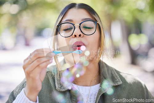 Image of Face of woman blowing bubbles in park, garden and freedom for fun, good mood and carefree personality. Happy, young and female gen z girl with soap bubble wand outdoor to relax on summer holiday