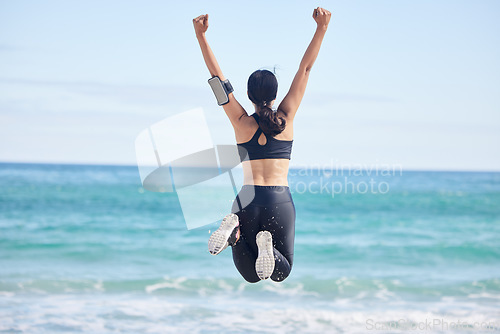 Image of Happy woman, fitness and jump in achievement on beach for winning, workout success or outdoor exercise. Rear view of excited female person in celebration for accomplishment or training by the ocean