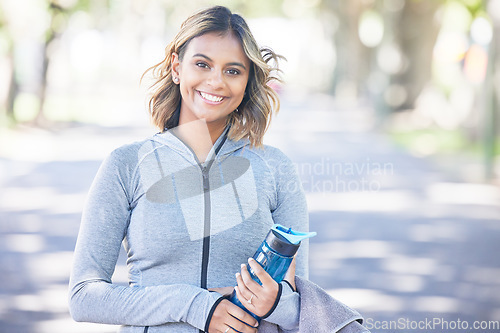 Image of Nature, fitness and portrait of a woman with a water bottle for an outdoor workout or training. Sports, happy and young female athlete with a smile in a park for a running cardio exercise in a garden