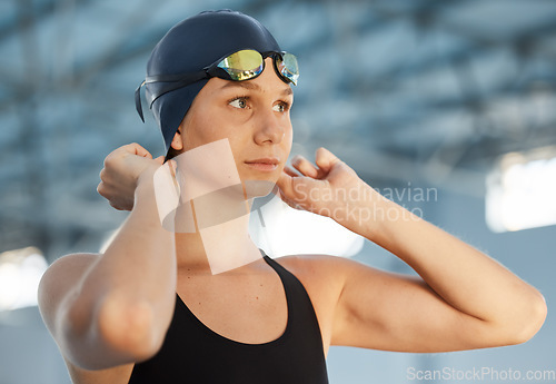 Image of Sports, cap and a woman swimmer getting ready for an event, race or competition in a gym. Fitness, exercise and workout with a young female athlete thinking while training at a swimming pool