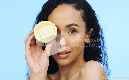 Image of Lemon, face skincare and beauty of woman in studio, vegan wellness or blue background. Model, portrait and citrus fruits for facial cosmetics, vitamin c aesthetic or healthy natural detox dermatology