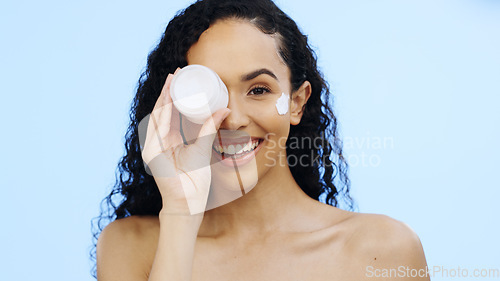 Image of Face, cream jar and beauty of woman, cosmetics and smile on blue background. Facial lotion, skincare and portrait of happy studio model with container for shine, natural wellness and aesthetic makeup