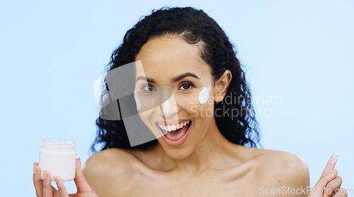 Image of Face, cream and beauty of woman with cosmetics, smile and sunscreen on blue background. Facial skincare, lotion jar and portrait of happy model with product for shine, happiness and aesthetic makeup