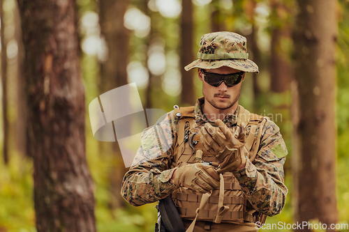 Image of American marine corps special operations soldier preparing tactical and commpunication gear for action battle closeup