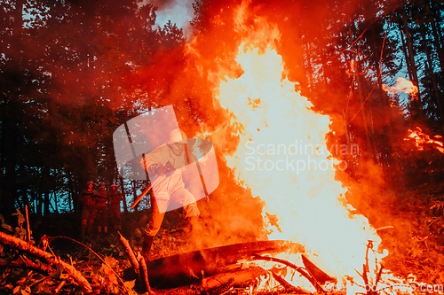 Image of firefighter hero in action danger jumping over fire flame to rescue and save