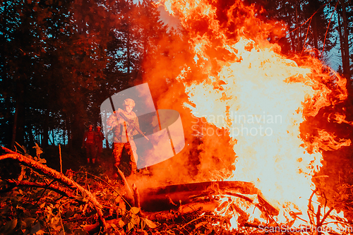 Image of Soldier in Action at Night in the Forest Area. Night Time Military Mission jumping over fire