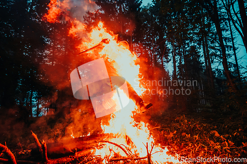 Image of Soldier in Action at Night in the Forest Area. Night Time Military Mission jumping over fire