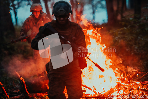 Image of Soldier in Action at Night in the Forest Area. Night Time Military Mission jumping over fire