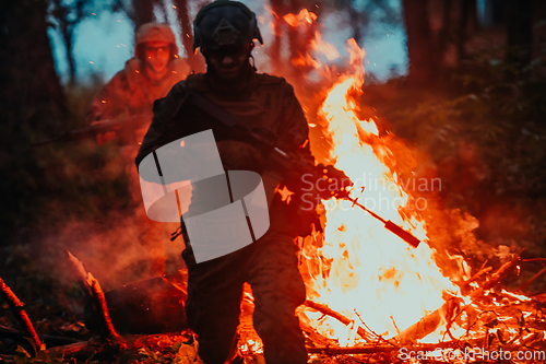 Image of Soldier in Action at Night in the Forest Area. Night Time Military Mission jumping over fire