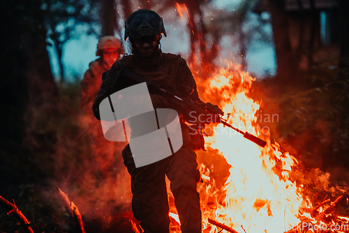 Image of Soldier in Action at Night in the Forest Area. Night Time Military Mission jumping over fire