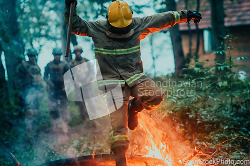 Image of firefighter hero in action danger jumping over fire flame to rescue and save