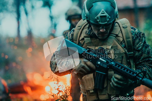 Image of Soldier in Action at Night in the Forest Area. Night Time Military Mission jumping over fire