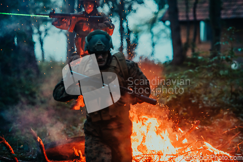 Image of Soldier in Action at Night in the Forest Area. Night Time Military Mission jumping over fire