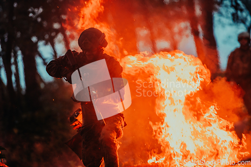 Image of Soldier in Action at Night in the Forest Area. Night Time Military Mission jumping over fire