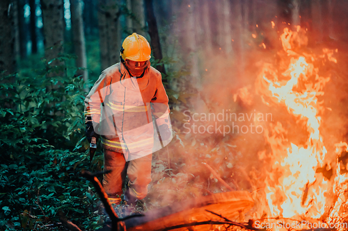 Image of firefighter hero in action danger jumping over fire flame to rescue and save