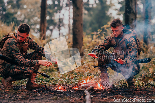 Image of Two exhausted soldiers sitting by the fire after a weary and heavy war battle