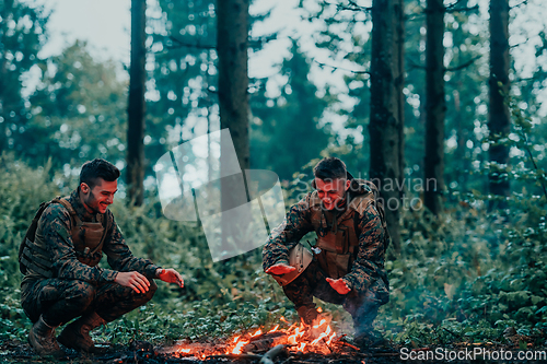 Image of Two exhausted soldiers sitting by the fire after a weary and heavy war battle