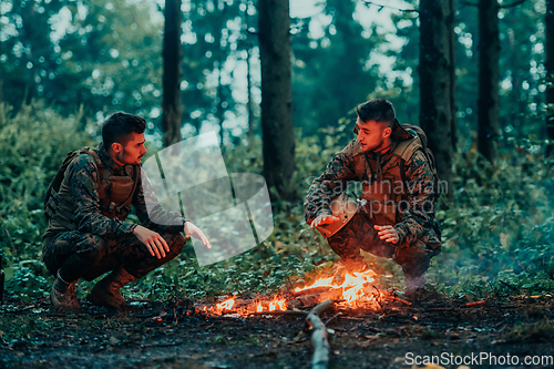 Image of Two exhausted soldiers sitting by the fire after a weary and heavy war battle