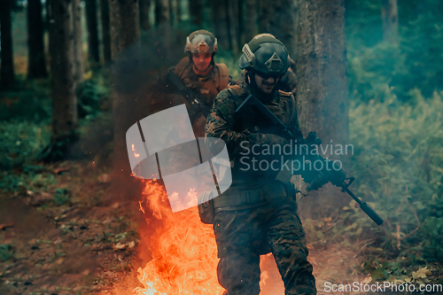 Image of Soldier in Action at Night in the Forest Area. Night Time Military Mission jumping over fire