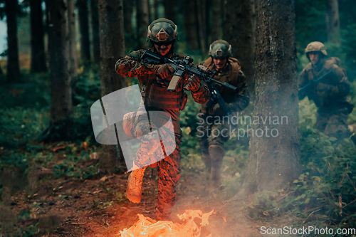 Image of Soldier in Action at Night in the Forest Area. Night Time Military Mission jumping over fire