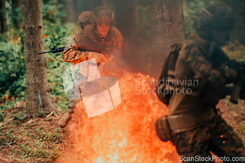 Image of Soldier in Action at Night in the Forest Area. Night Time Military Mission jumping over fire