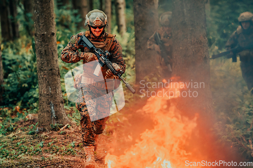 Image of Soldier in Action at Night in the Forest Area. Night Time Military Mission jumping over fire