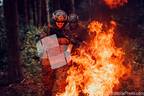 Image of Soldier in Action at Night in the Forest Area. Night Time Military Mission jumping over fire