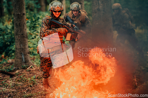 Image of Soldier in Action at Night in the Forest Area. Night Time Military Mission jumping over fire