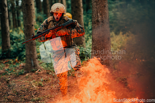 Image of Soldier in Action at Night in the Forest Area. Night Time Military Mission jumping over fire