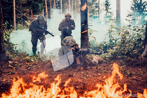 Image of Modern warfare soldiers surrounded by fire fight in dense and dangerous forest areas