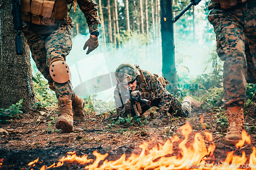 Image of Modern warfare soldiers surrounded by fire fight in dense and dangerous forest areas