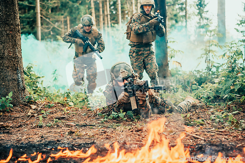 Image of Modern warfare soldiers surrounded by fire fight in dense and dangerous forest areas