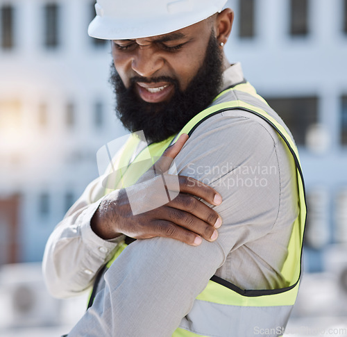 Image of Injury, arm pain and a black man construction worker on a building site, feeling fatigue in his shoulder. Burnout, emergency or accident and a male engineer holding his muscle with inflammation