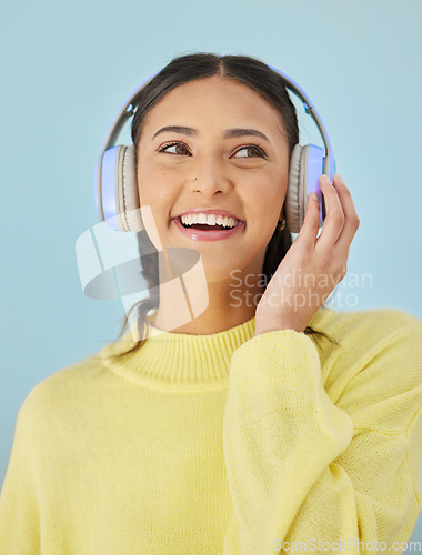 Image of Woman with smile, headphones and mockup in studio for podcast, mobile app and streaming radio site. Sound, music subscription and happy girl listening to audio on earphones on blue background space.