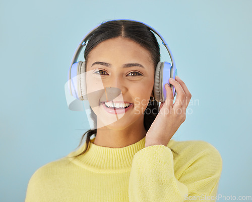 Image of Portrait of happy woman, headphones and mockup in studio listening to podcast, mobile app and streaming radio site. Smile, music media subscription and sound, face of girl on blue background space.