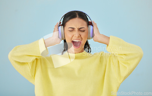 Image of Music, screaming and headphones with a woman in studio on a gray background while streaming audio. Radio, shouting or expression and an angry young female person listening to sound or loud noise