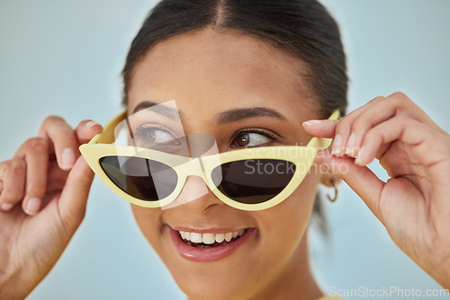 Image of Smile, sunglasses and young woman in a studio with a casual, stylish and cool eyewear. Happy, excited and female model with trendy gen z style and fashion accessory isolated by a blue background.