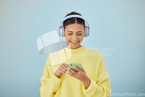 Image of Woman with phone, headphones and mockup in studio for social media post, mobile app and streaming radio site. Smile, music media subscription and happy girl with cellphone on blue background space.