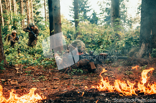 Image of Modern warfare soldiers surrounded by fire fight in dense and dangerous forest areas