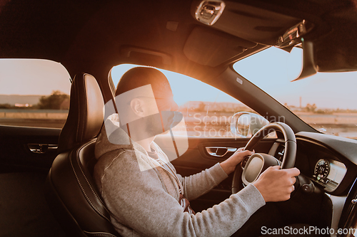 Image of A man with a sunglasses driving a car at sunset. The concept of car travel