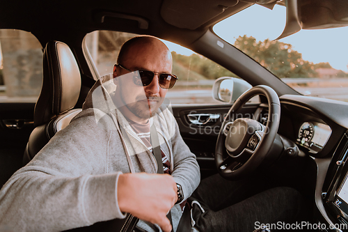 Image of A man with a sunglasses driving a car at sunset. The concept of car travel