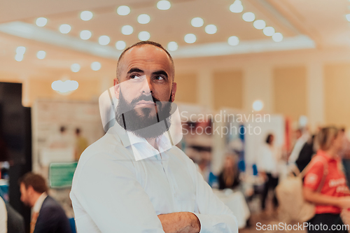 Image of Portrait of a business man with a beard. In the background, a group of business people preparing for the start of the conference