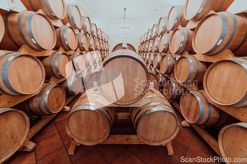 Image of Wine or cognac barrels in the cellar of the winery, Wooden wine barrels in perspective. Wine vaults.Vintage oak barrels of craft beer or brandy.