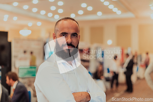 Image of Portrait of a business man with a beard. In the background, a group of business people preparing for the start of the conference