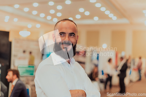 Image of Portrait of a business man with a beard. In the background, a group of business people preparing for the start of the conference