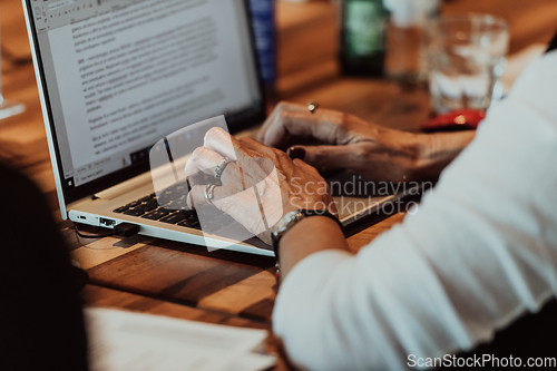 Image of Close up photo of an elderly woman typing on a laptop at a seminar