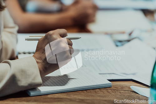 Image of Closeup shot of business people hands using pen while taking notes on education training during business seminar at modern conference room