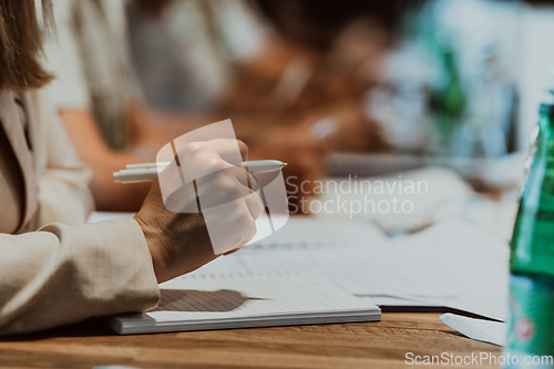 Image of Closeup shot of business people hands using pen while taking notes on education training during business seminar at modern conference room