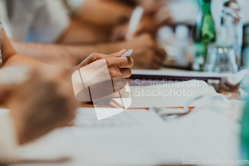 Image of Closeup shot of business people hands using pen while taking notes on education training during business seminar at modern conference room